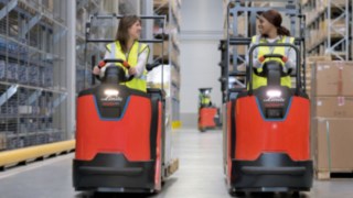 Zwei Mitarbeiterinnen in Kommissionierern der N20 Serie von Linde Material Handling Zwei Mitarbeiterinnen fahren im Lager mit Kommissionierern der N20 Serie von Linde Material Handling.