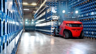 Die Doppelpedalsteuerung der Linde-Stapler sorgt für schnelles Reversieren und verkürzt die Zeit der Lkw-Beladung. Ein Linde E-Stapler vor blauen Getränkekisten.